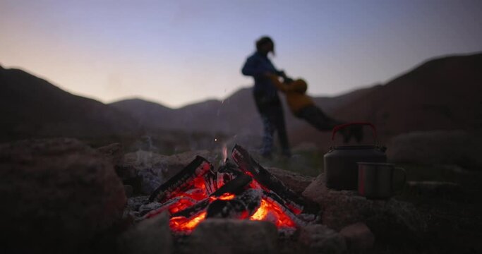 Woman and child play together. Mom spins baby around holding hands. Campfire burning out in foreground, mother and son campers tourists in background having fun, having good time together. Slow motion
