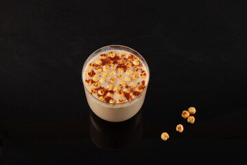 Glass of Boza Drink or Bosa on dark table, top view. Traditional Turkish fermented drink with...