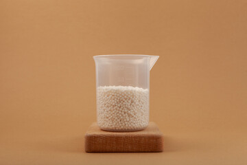 Chemical fertilizer in plastic measuring cup. Small white balls. Agricultural economics. Test fertilizer
