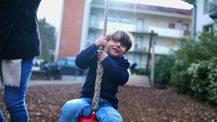 Child holding into wire slide at public park during autumn fall season. Kid gripping rope in...