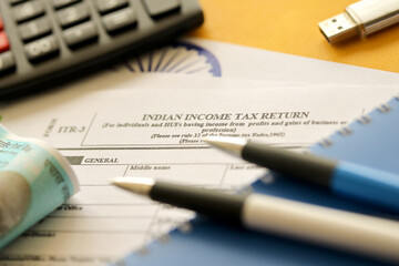 Indian income tax return blank form with pen and indian rupees bills on indian country flag close...