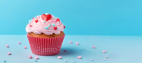 Foto op Plexiglas festive cupcake with pink icing, decorated with small red hearts, on blue background, copy space,banner, concept of sweet gift for Valentine's Day and birthday © Наталья Лазарева