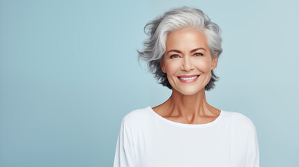 beautiful elderly woman model with beautiful gray hair posing in the studio on a pastel blue background. advertising beauty photo shoot. health and graceful aging. copy space. banner - obrazy, fototapety, plakaty
