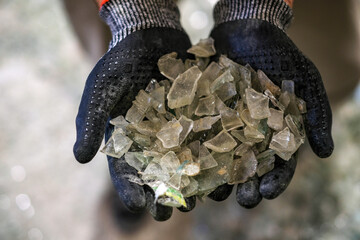 An operator shows a handful of white glass to recycle - obrazy, fototapety, plakaty