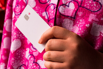 Woman wearing pink cloths with hearts and holding white credit card