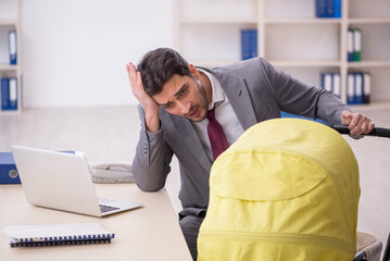 Young male employee looking after newborn at workplace