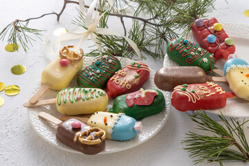 Christmas dessert. Sweet food. Cheesecake on a stick in the shape of ice cream. Children's treat in winter. Candy Christmas tree, snowman, deer and Santa Claus. Gingerbread cookies.