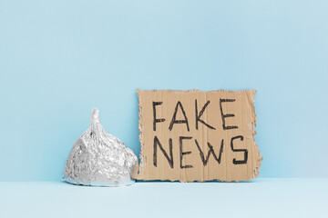 Aluminium foil hat and fake news poster on blue background, symbol for conspiracy theory and mind...