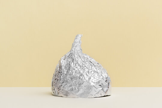 Aluminium foil hat on beige background, symbol for conspiracy theory and mind control protection. Top view