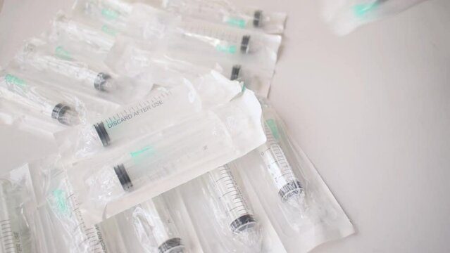 Hand taking syringe in package from white background 