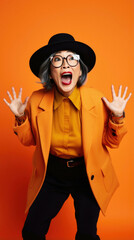 Middle age senior woman with grey hair wearing casual coat and glasses over orange background celebrating mad crazy for success and arms arms raised and closed eyes screaming.