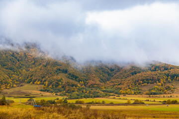 Idyllic Autumn Scenery with Fluffy Clouds and Colorful Mountains in the Background
