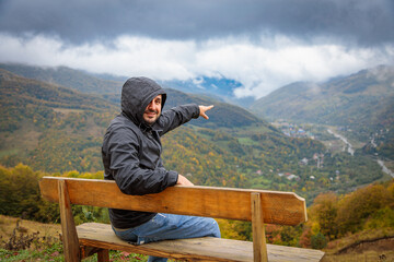 Man Enjoying Scenic Mountain View While Relaxing on Observation Deck Bench