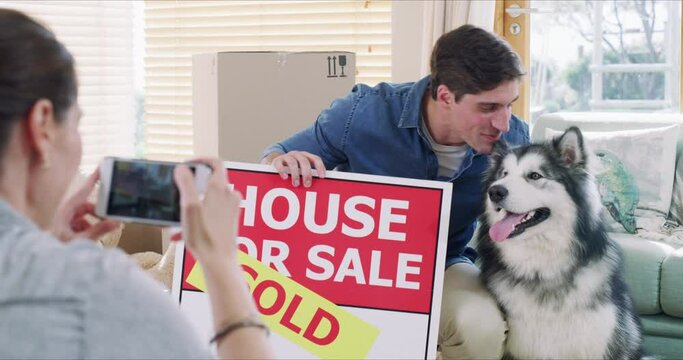 Man, dog and sold for sign by new home with photo by phone for memory, milestone or goal. Woman taking picture, husky and kiss with smile for bond, love and care for property, real estate or growth
