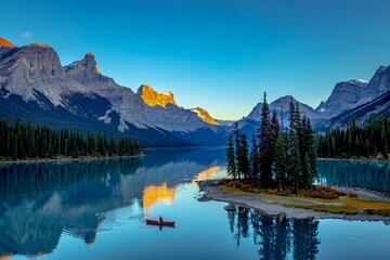 a tranquil mountain lake, surrounded by majestic snow-capped mountains, Morine lake Canada - Powered by Adobe