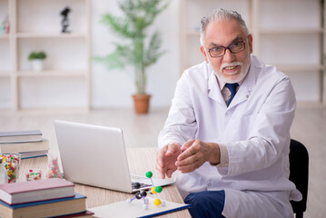 Old male doctor holding molecular model