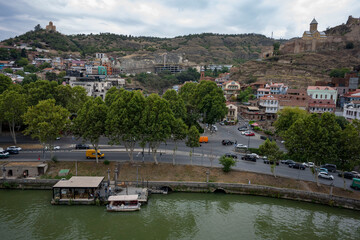 Fototapeta premium The Kura River running through Tbilisi, bridges and boats cruising on the river. 