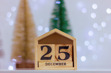 wooden calendar with date December 25 on the background of holiday lights. winter holidays and celebrations.