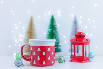 Christmas festive decor and red cup with pattern of white fir trees on table. decorations, celebration, winter holiday