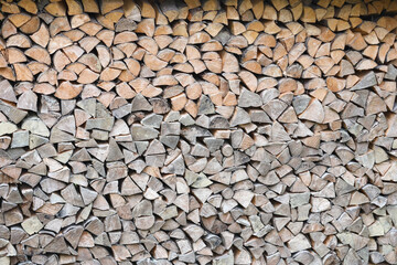 Firewood stacked near the wooden wall of old hut. Many chopped logs of firewood close up