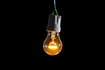 Glowing vintage light bulb close up on black background
