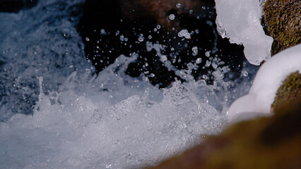 CLOSE UP: Flying water drops of a lively and splashing alpine mountain creek