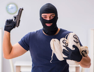 Robber wearing balaclava stealing valuable things