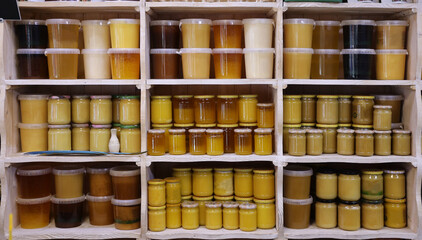 Jars of different honey varieties stocked on a shelf. Lavender, linden and mixed honey close up