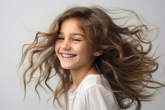 Young girl with joyful expression on her face, her hair blowing in wind. This image can be used to convey happiness, carefree spirit, or beauty of nature