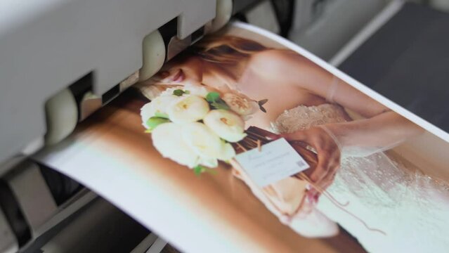 The process of printing wedding photos on a printer in a darkroom.