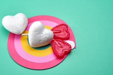 Two red heart-shaped lollipops on top of a rainbow with a pure white heart. Concept of pure love.
