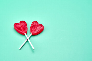 Two heart-shaped lollipops on a green background representing love.