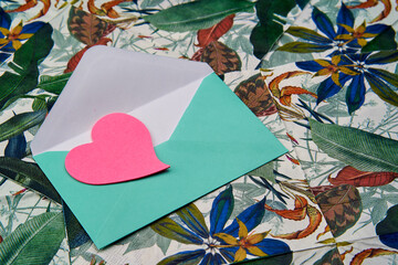 Blue envelope for a love letter with a heart on a tropical background.