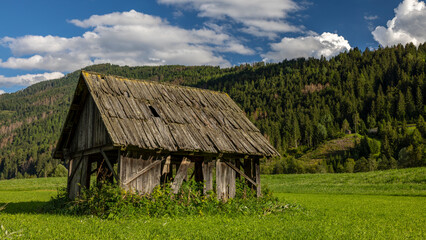 eine alte Bauernhütte auf einer grünen Wiese