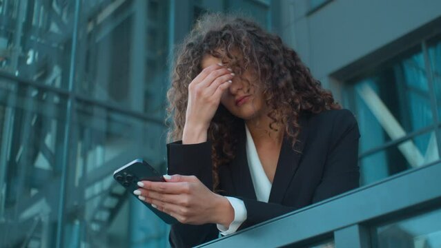 Caucasian young girl business woman employee worker tired exhausted upset stressed sad businesswoman on office balcony outside problem failure mobile phone bad news smartphone message in city outdoors