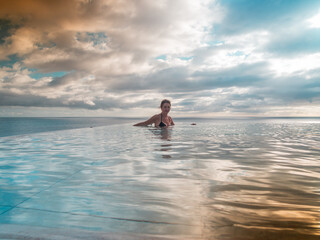 Portrait of a woman standing in an infinity pool looking over the sea