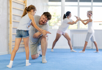 Parents and children during training and self-defense workout. Training moment of neutralizing enemy, transformation of attack into defense. - obrazy, fototapety, plakaty