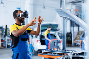 Expert in auto repair shop using virtual reality to visualize car ignition system in order to fix it. BIPOC experienced garage worker wearing futuristic vr headset while working on faulty vehicle - obrazy, fototapety, plakaty