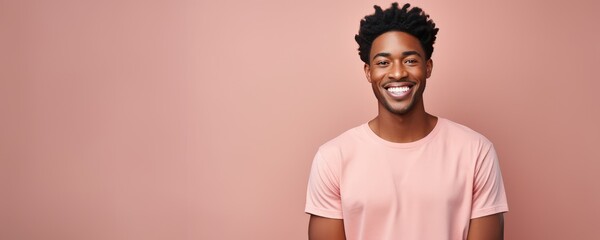 Fototapeta premium Portrait of a young black man smiling against a pastel pink background