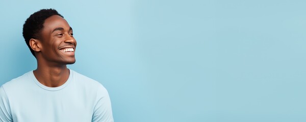 Portrait of a young black man smiling against a pastel blue background