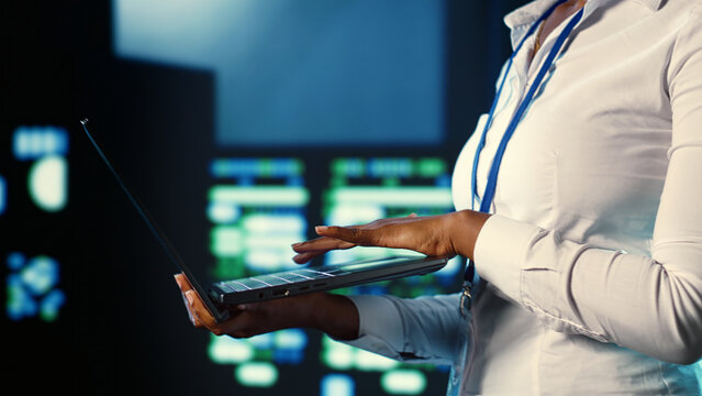 System administrator programming in server farm housing advanced equipment storing massive datasets. Programmer running code on laptop to mend data center racks doing complex computational operations