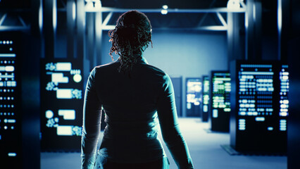 Skillful employee strolling around data center server rows, looking for damages in high tech...