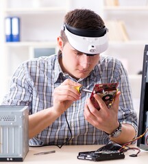 Young technician repairing computer in workshop