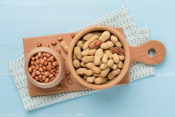 Peeled and unpeeled peanuts on wooden background, top view
