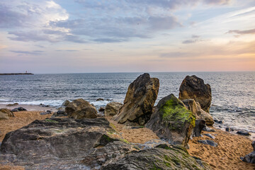 Landscape of the picturesque sandy coast of the Atlantic Ocean with large brown stones at sunset. Porto, Portugal.