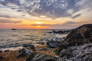 Landscape of the picturesque sandy coast of the Atlantic Ocean with large brown stones at sunset. Porto, Portugal.