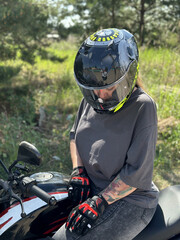 young woman in a helmet and gloves on a motorcycle