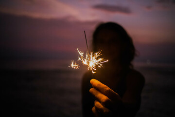 woman holding sparkles celebrating on tropical beach