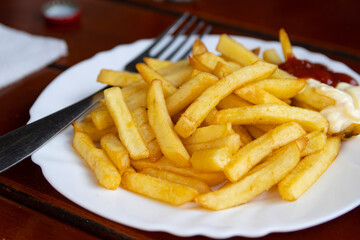 Pommes frites - also called chips or French fries - served with ketchup and mayonnaise condiments on the side.
