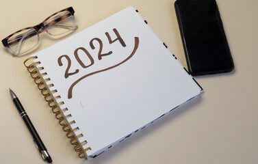 Notepad with 2024 lettering, pen and embellishments on light background. For postcards, social...